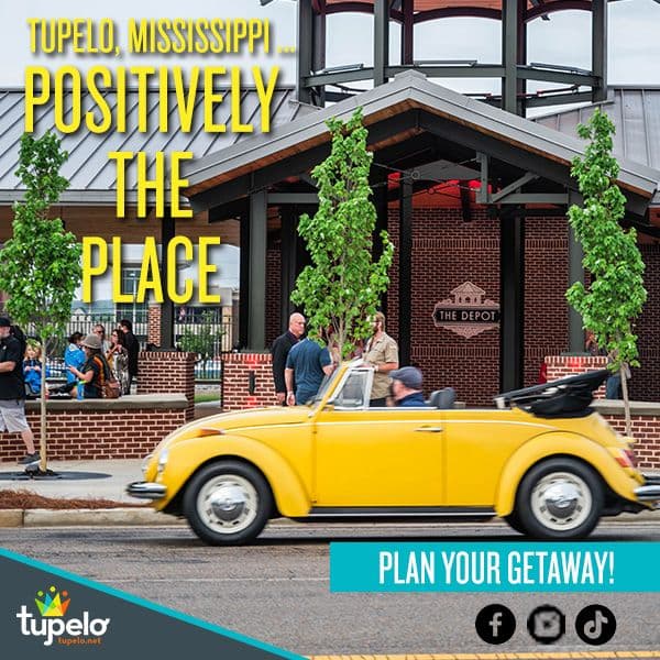 Yellow convertible driving past The Depot in Tupelo, Mississippi, with people gathered outside. Text reads, "Positively the Place. Plan Your Getaway!"